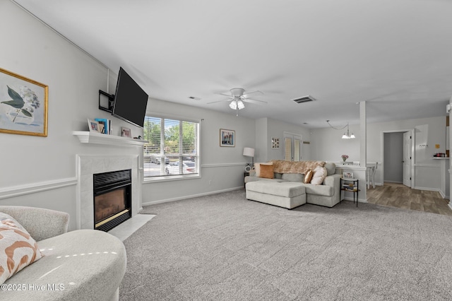 carpeted living area with a ceiling fan, baseboards, visible vents, and a fireplace