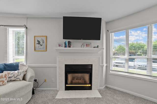 living area featuring carpet floors, a wealth of natural light, and a tile fireplace