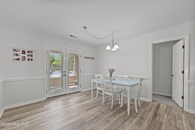 dining room with visible vents, wood finished floors, french doors, and an inviting chandelier