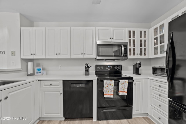 kitchen with white cabinets, glass insert cabinets, black appliances, and a toaster
