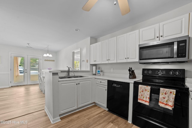 kitchen featuring a sink, white cabinets, black appliances, and a peninsula
