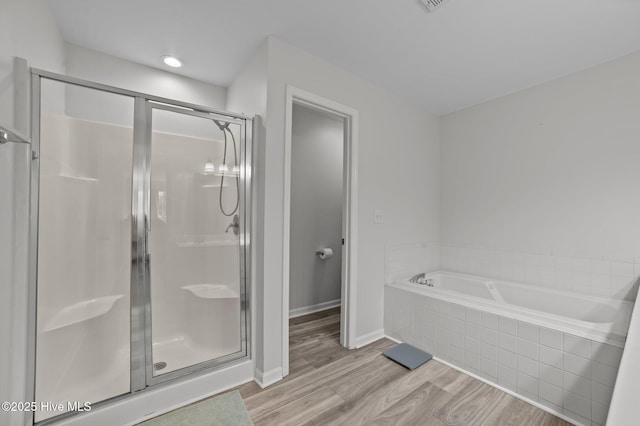bathroom with a bath, baseboards, a shower stall, and wood finished floors