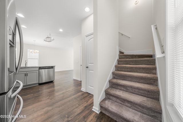 stairs with recessed lighting, a notable chandelier, baseboards, and wood finished floors