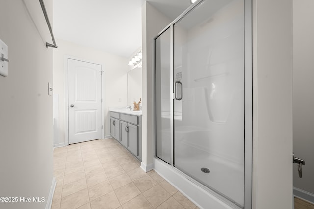 full bathroom with a stall shower, vanity, baseboards, and tile patterned flooring
