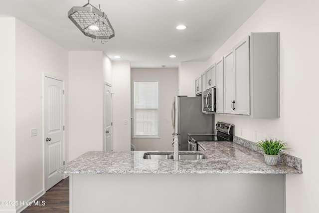kitchen featuring dark wood-style flooring, recessed lighting, a peninsula, light stone countertops, and stainless steel appliances
