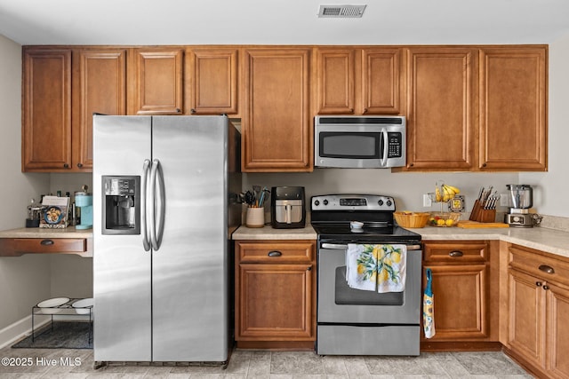 kitchen featuring brown cabinets, light countertops, stainless steel appliances, and visible vents