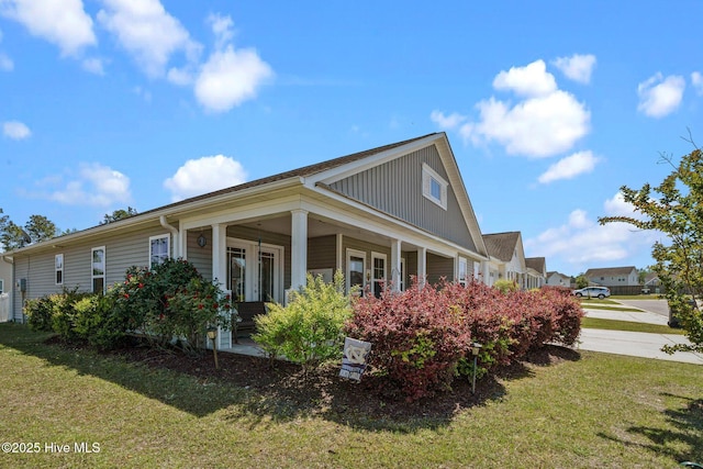 view of side of property featuring covered porch and a lawn