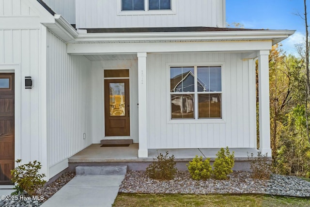 view of exterior entry featuring board and batten siding and a shingled roof