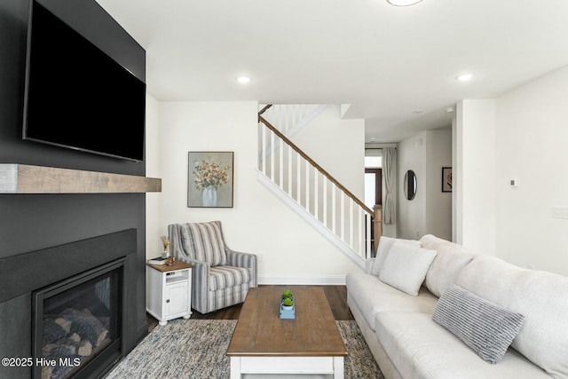 living area featuring a glass covered fireplace, recessed lighting, stairway, wood finished floors, and baseboards