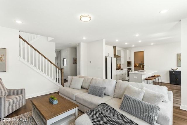 living area featuring wood finished floors, recessed lighting, baseboards, and stairs