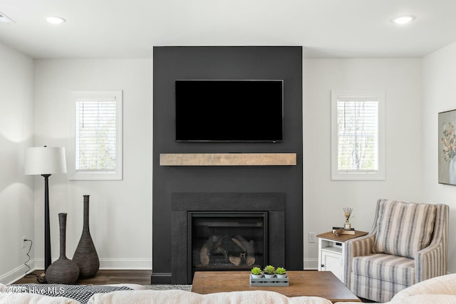 living room featuring baseboards, recessed lighting, wood finished floors, and a fireplace