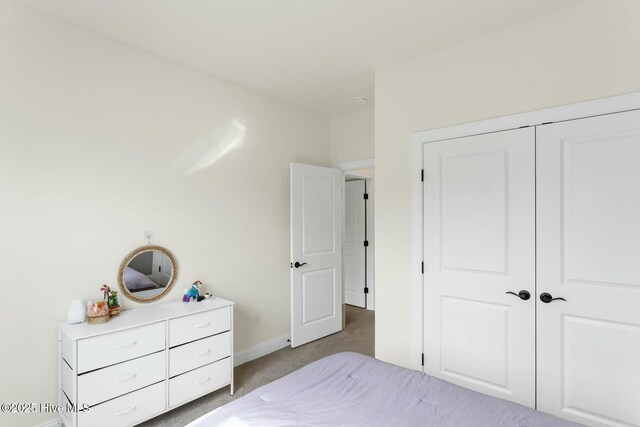carpeted bedroom with a closet and baseboards