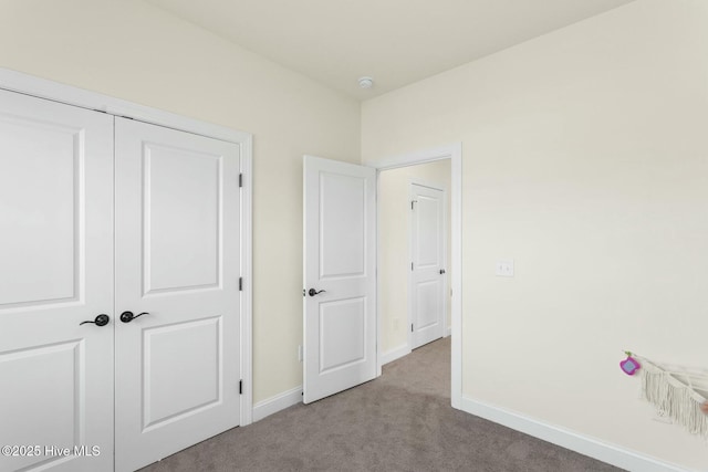 unfurnished bedroom featuring a closet, baseboards, and carpet