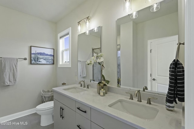bathroom with tile patterned floors, double vanity, a sink, and toilet