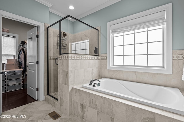 bathroom featuring a shower stall, a walk in closet, a bath, and ornamental molding