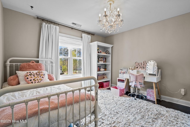 bedroom with visible vents, baseboards, a notable chandelier, and wood finished floors