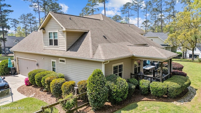 view of home's exterior with an attached garage, a shingled roof, driveway, and a lawn
