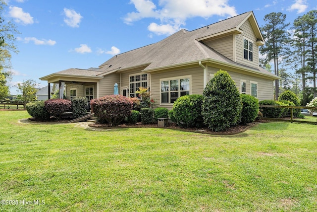 rear view of property with roof with shingles and a lawn
