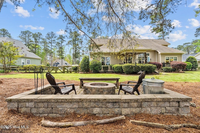 back of property with a yard, a fire pit, and fence