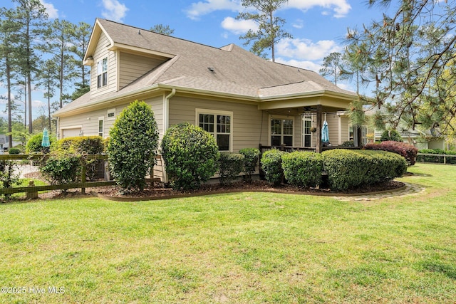view of property exterior with a yard, fence, and a shingled roof