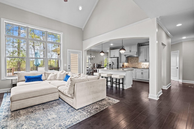 living room with arched walkways, baseboards, ornamental molding, and recessed lighting