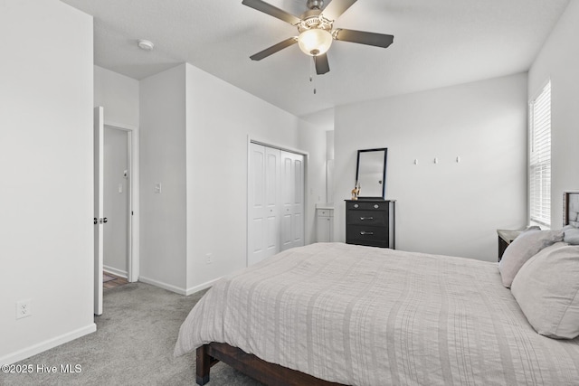 carpeted bedroom with a closet, baseboards, and ceiling fan