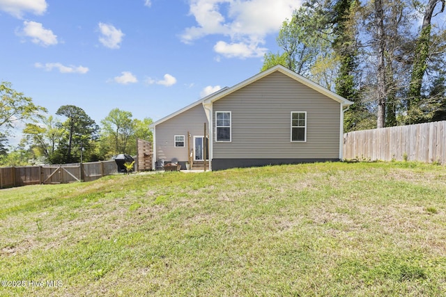 rear view of property with a yard, entry steps, and a fenced backyard