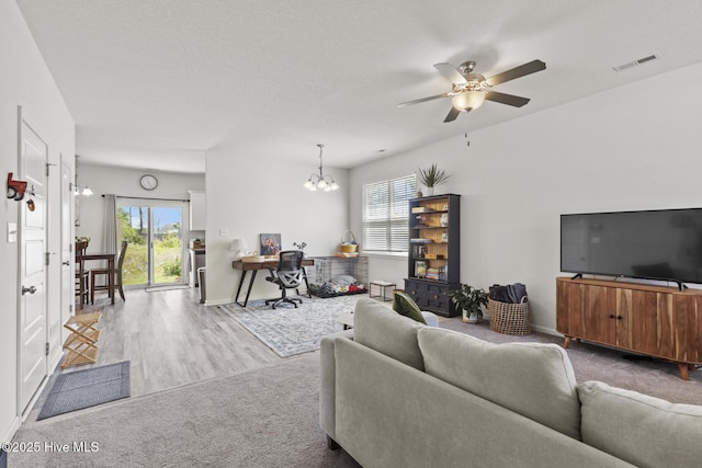 living room with visible vents, baseboards, carpet flooring, and ceiling fan with notable chandelier