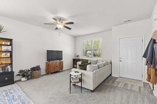 carpeted living area with visible vents, baseboards, and a ceiling fan