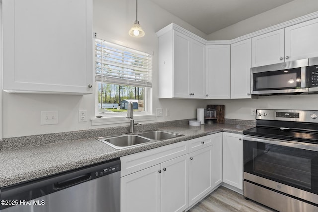 kitchen with stainless steel appliances, light wood-type flooring, white cabinetry, and a sink