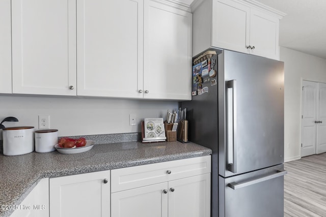 kitchen featuring light wood-type flooring, white cabinets, and freestanding refrigerator