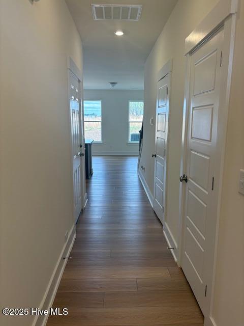 hallway with recessed lighting, visible vents, baseboards, and wood finished floors