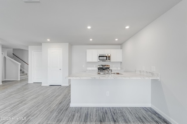 kitchen featuring light wood-style flooring, white cabinetry, recessed lighting, stainless steel appliances, and baseboards