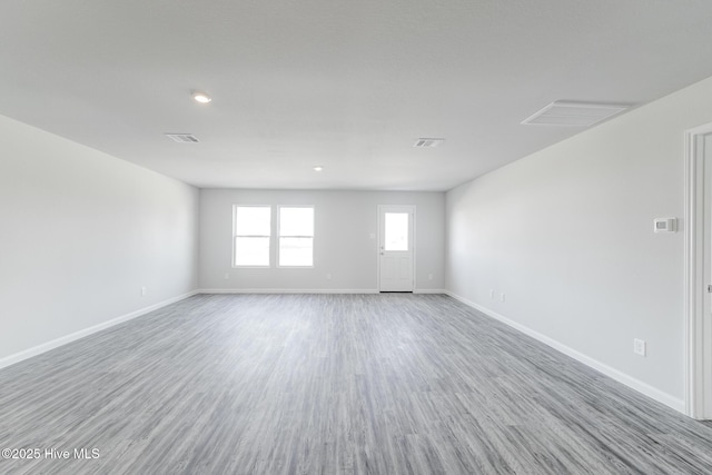 empty room with wood finished floors, baseboards, and visible vents