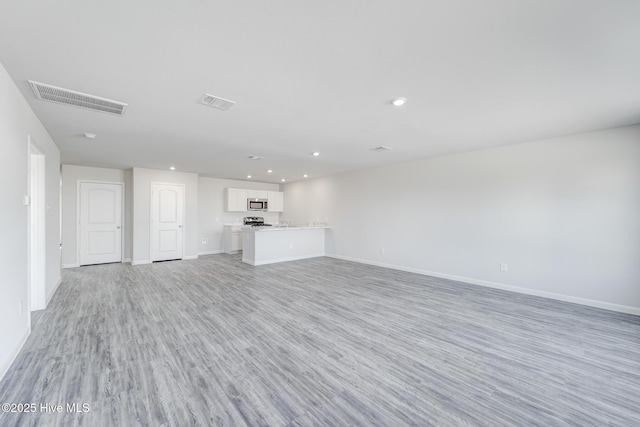 unfurnished living room with light wood-style floors, recessed lighting, visible vents, and baseboards