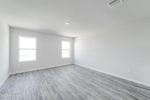 unfurnished room featuring visible vents, baseboards, and wood finished floors
