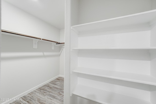 walk in closet with wood finished floors