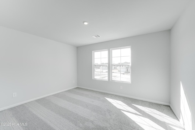 spare room with carpet, visible vents, and baseboards