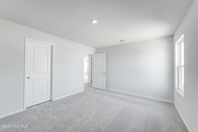 spare room featuring baseboards, visible vents, and carpet floors