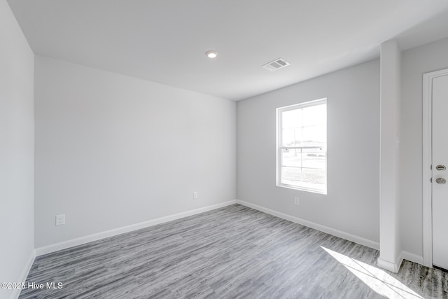 spare room featuring visible vents, baseboards, and wood finished floors