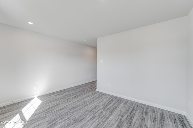 unfurnished room featuring wood finished floors, baseboards, and recessed lighting