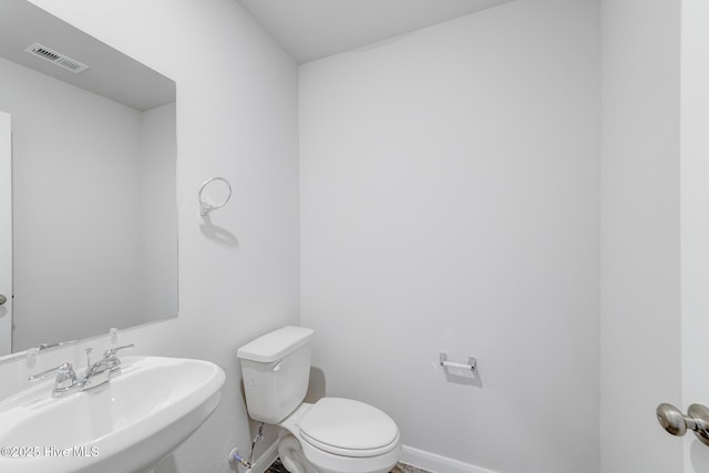 bathroom featuring toilet, baseboards, a sink, and visible vents