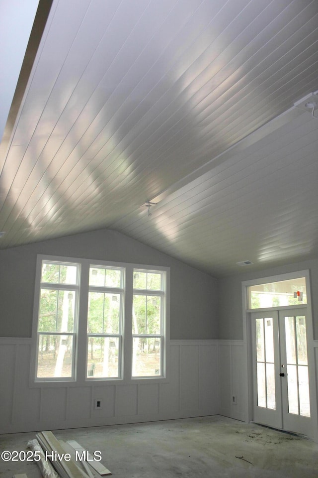 3359 Portside Dr SW, Supply, NC 28462 - unfurnished living room featuring french doors, vaulted ceiling, plenty of natural light, and wainscoting