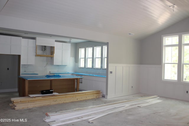 3359 Portside Dr SW, Supply, NC 28462 - kitchen featuring wainscoting, a kitchen island, white cabinets, vaulted ceiling, and a decorative wall