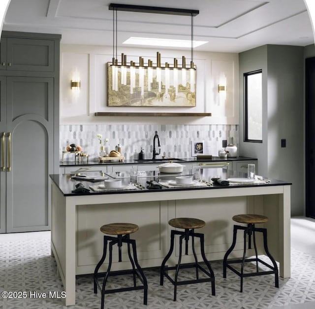 bar with hanging light fixtures, a sink, backsplash, and light floors