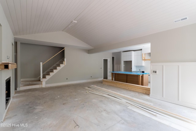 3359 Portside Dr SW, Supply, NC 28462 - unfurnished living room featuring stairway, vaulted ceiling, wainscoting, and a fireplace