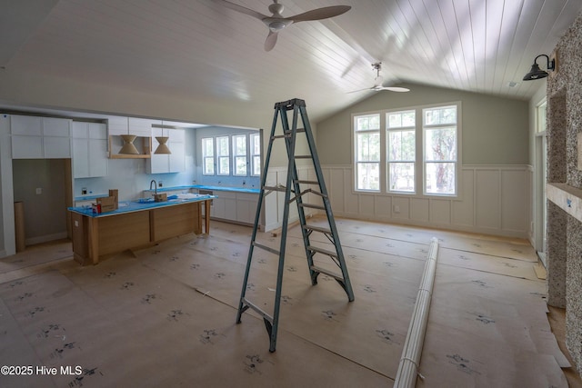 3359 Portside Dr SW, Supply, NC 28462 - kitchen with a ceiling fan, vaulted ceiling, a wainscoted wall, white cabinetry, and wood ceiling