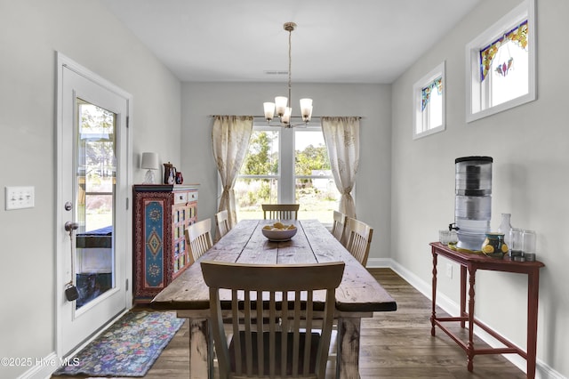 dining area featuring baseboards, a notable chandelier, wood finished floors, and visible vents