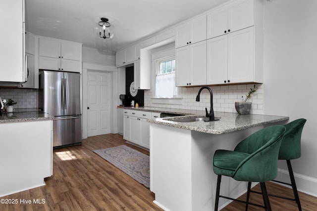 1508 Rhem Ave, New Bern, NC 28560 - kitchen featuring freestanding refrigerator, a sink, white cabinetry, a peninsula, and backsplash