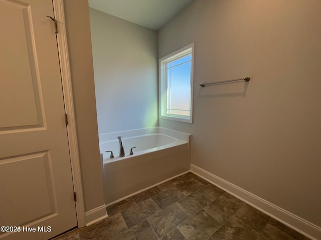 bathroom featuring a bath and baseboards